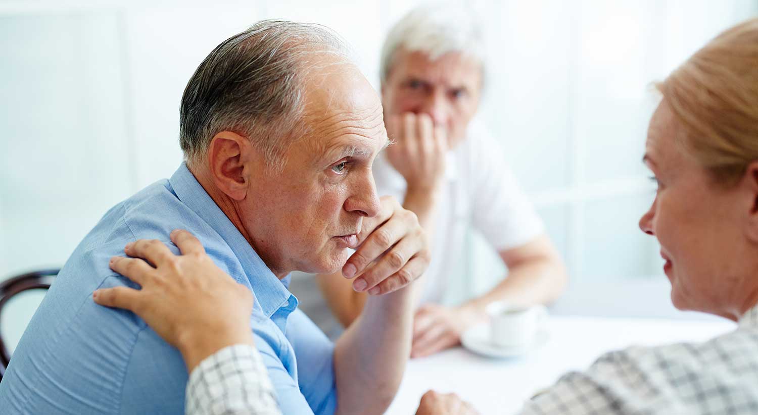 Women comforting a man with her hand on his shoulder