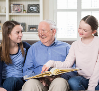 Grandfather sharing photos in a photo album with grandchildren. Palliative Care