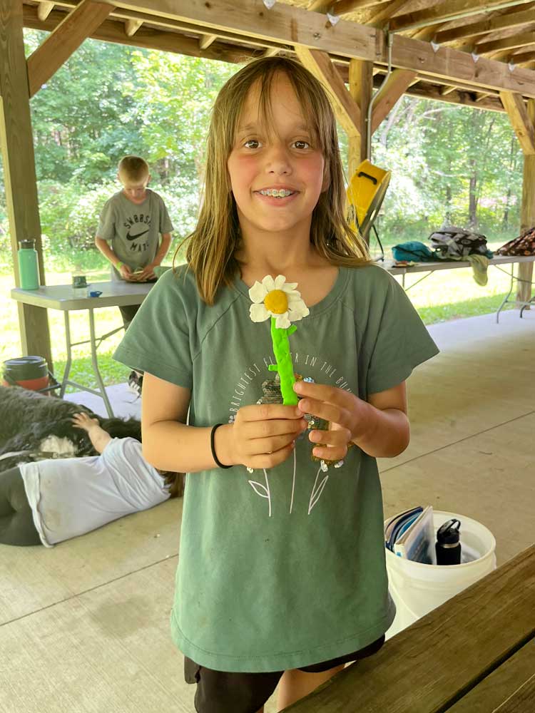 Camp Pathways North child holding clay flower