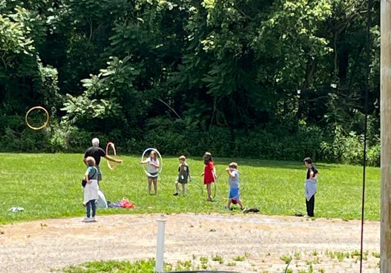 Camp Pathways Newark kids playing with hula hoops in a field